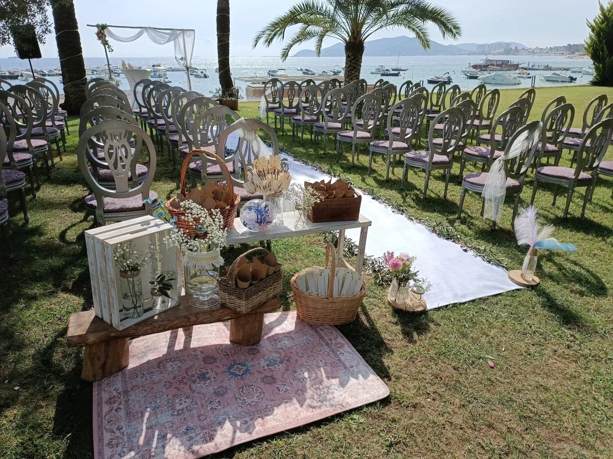 Torre del Mar: Ceremony set-up on the garden lawn with chairs, rugs and decorations facing the bay