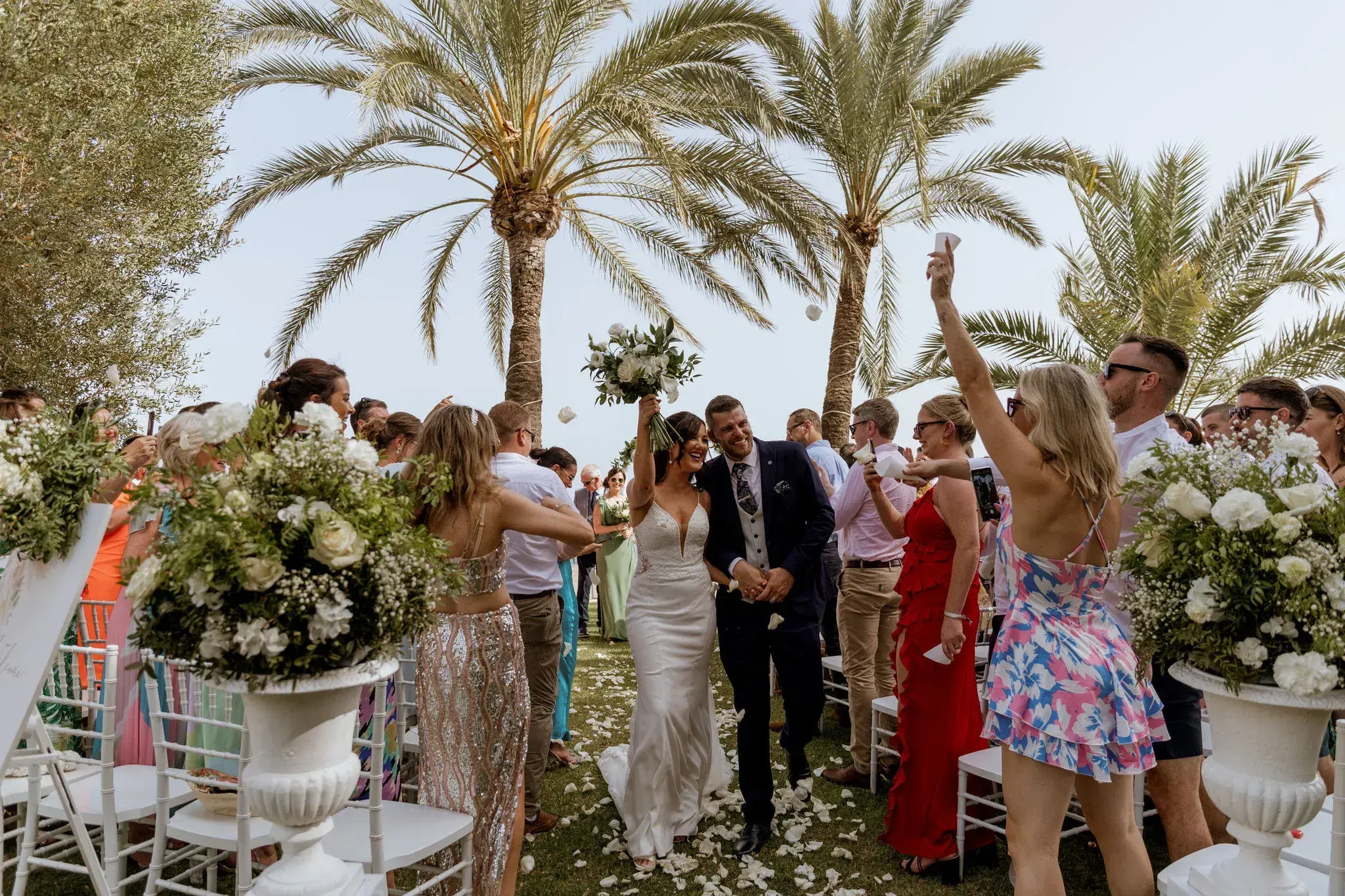 Torre del Mar: Newlyweds walking back down the aisle among cheering guests under palms