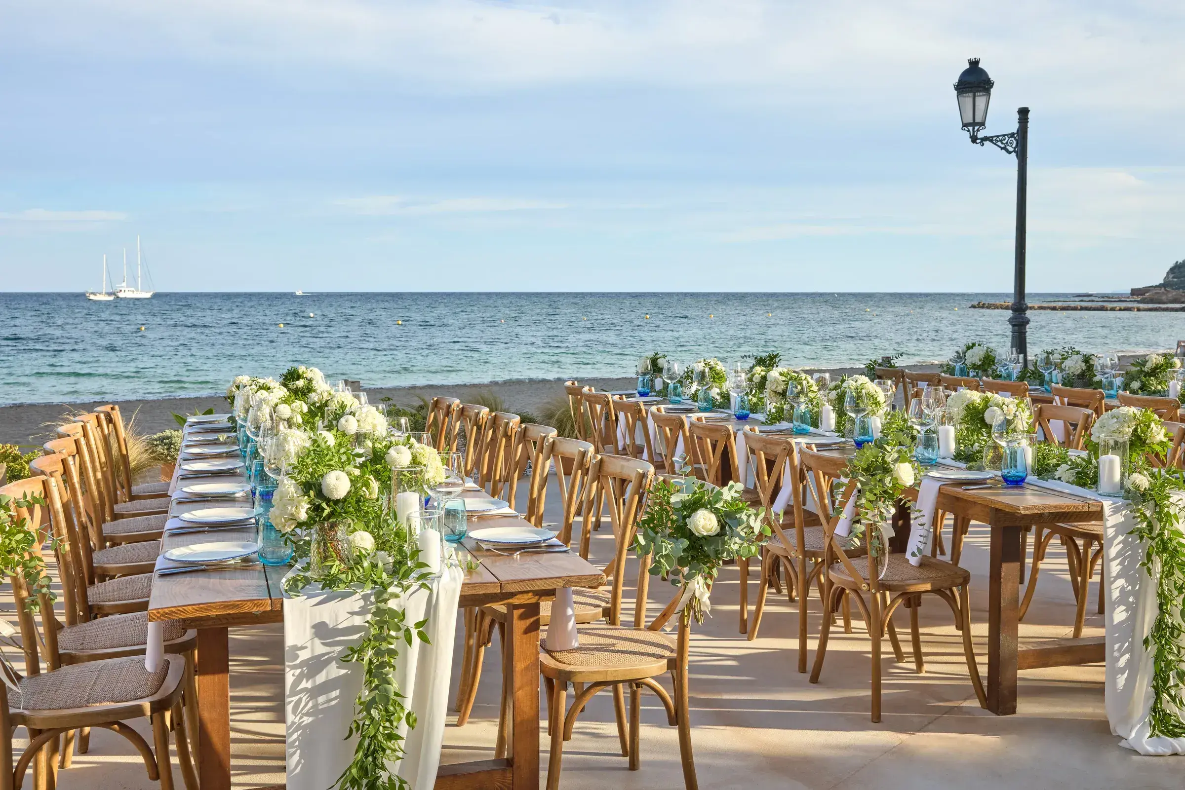 W Ibiza: Long wedding dinner tables with white flowers and greenery on the seafront terrace