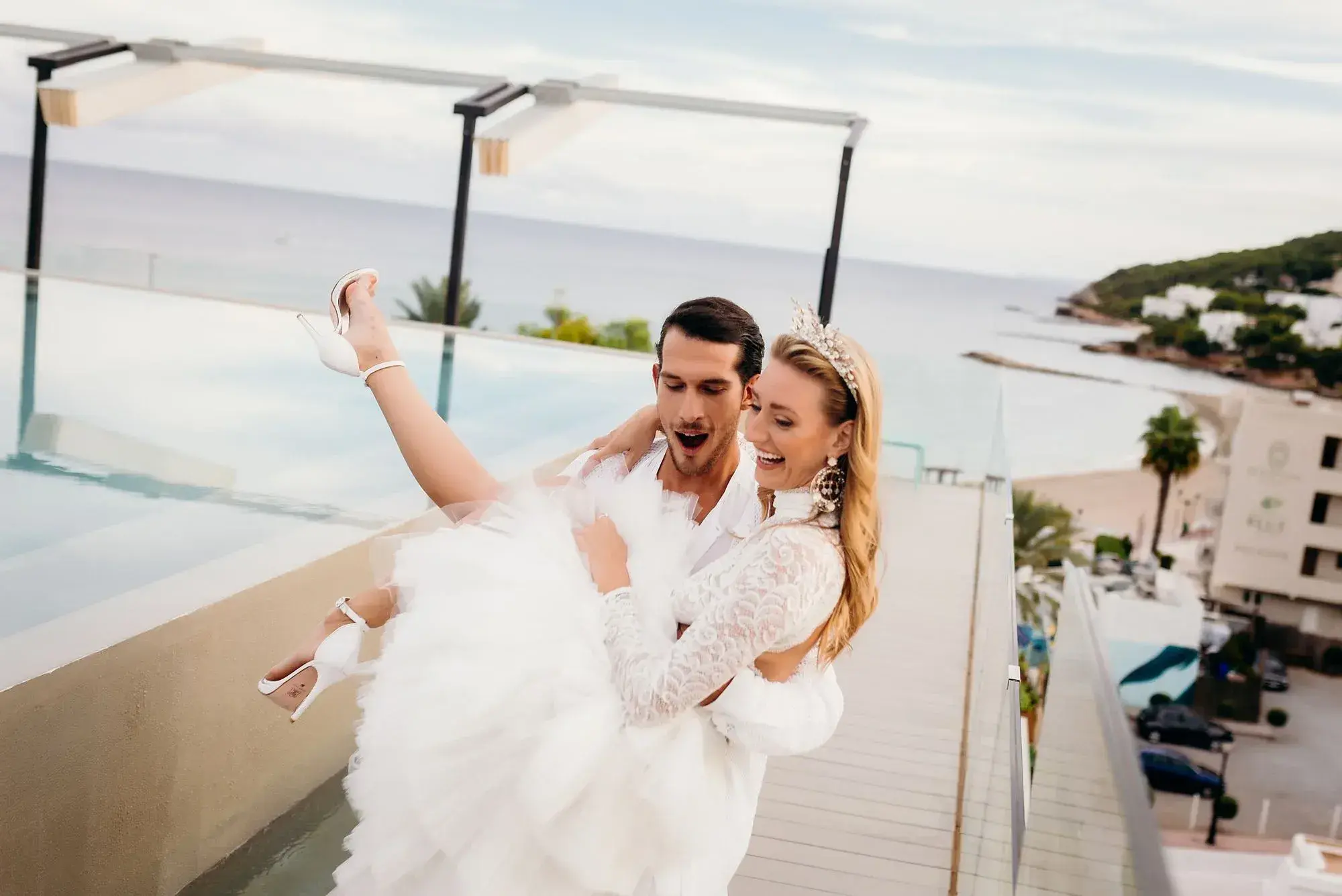 W Ibiza: Groom lifting the bride on the rooftop terrace above the beach