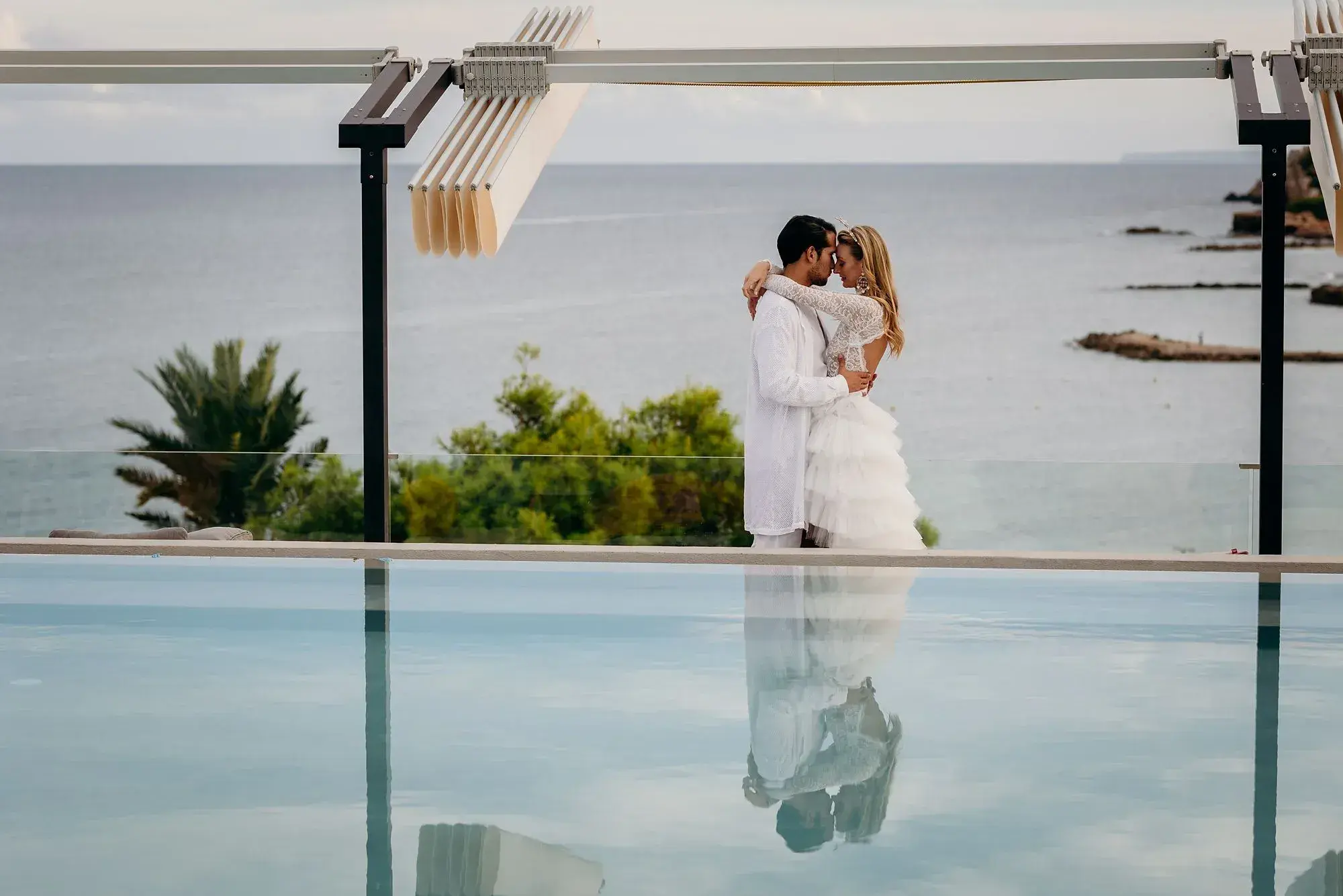 W Ibiza: Couple embracing by the rooftop pool edge with the sea behind